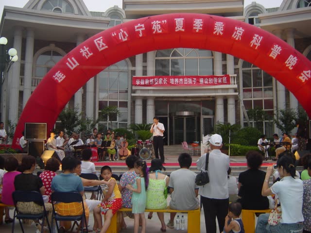 2002 年夏 · 大连连山社区「心宁苑」社区活动，横幅即「学做称职型家长，培养杰出孩子，建设和谐家庭」